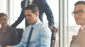 A man sitting in an office chair next to another man.