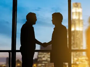 Two men shaking hands in front of a window.