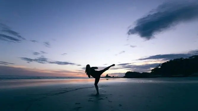 A woman is doing a kick stand on the beach