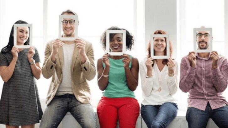 Three people holding up frames in front of their faces.